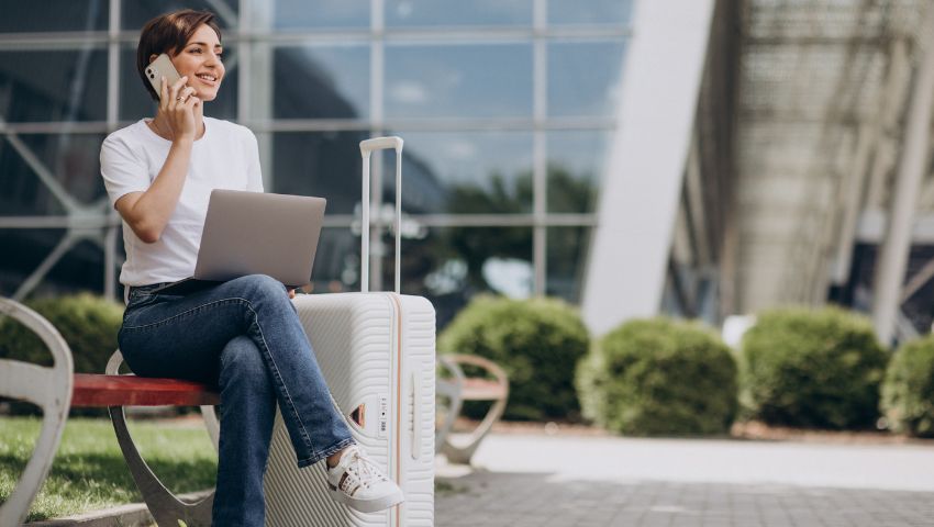 Donna che lavora al computer portatile in aeroporto, combinando lavoro e viaggio, simbolo del concetto di bleisure.